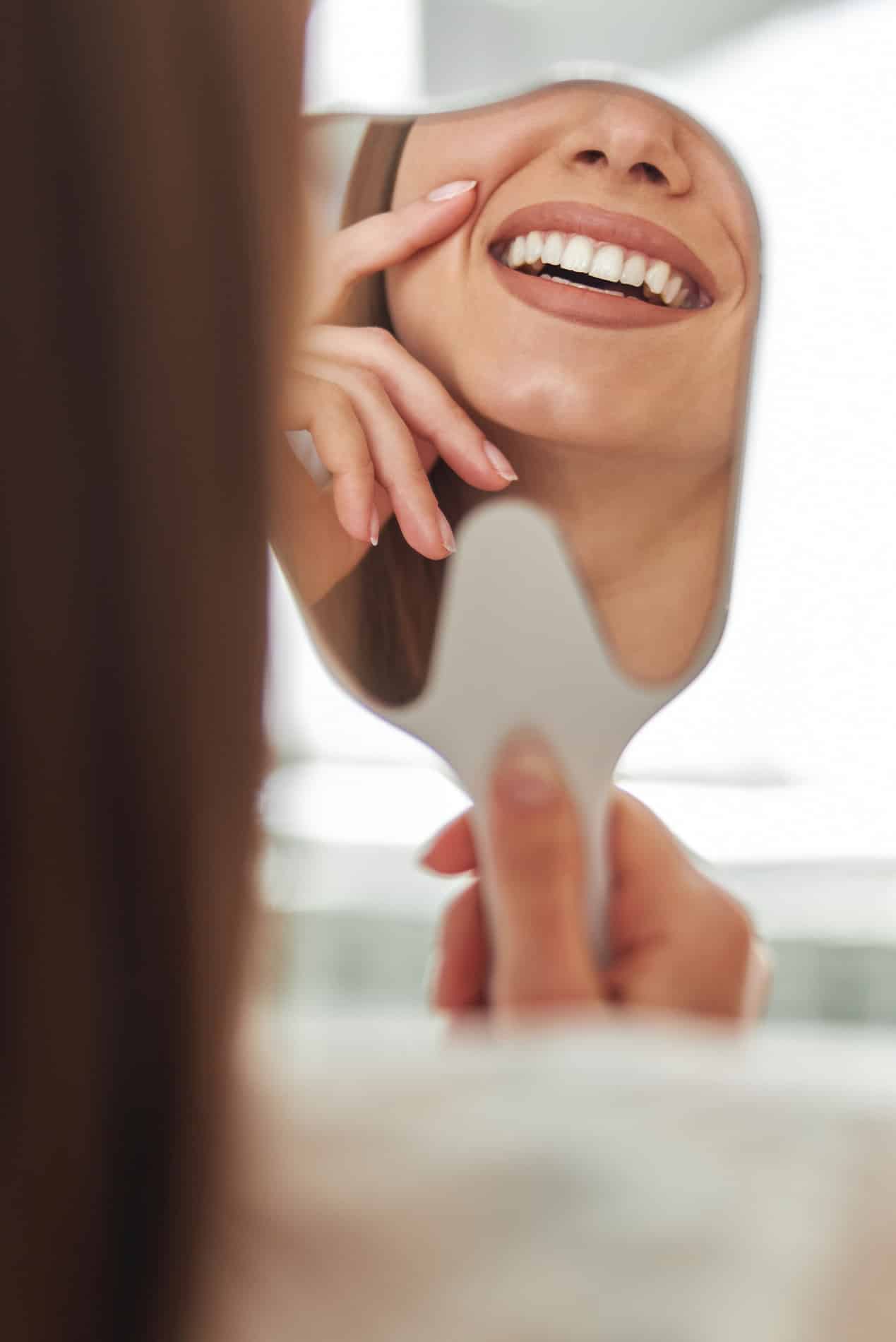 A young woman laying down in a dental chair smiling at esteem dental studio