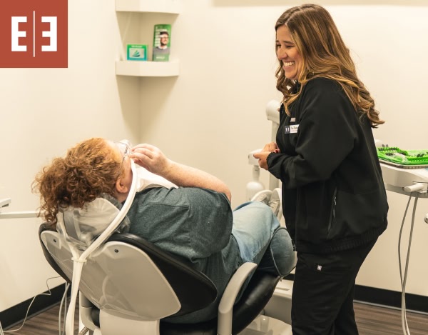 A young woman laying down in a dental chair smiling at esteem dental studio